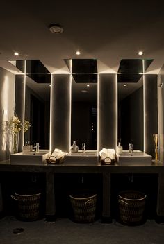 a bathroom with two sinks and mirrors in the wall above them is lit by lights