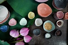 various bowls and spoons are arranged on a table next to pink tulips