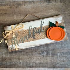 a wooden sign that says, happy thanksgiving with an orange pumpkin on it and the word grateful written in cursive font