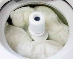 a close up of a white machine with cloths in it