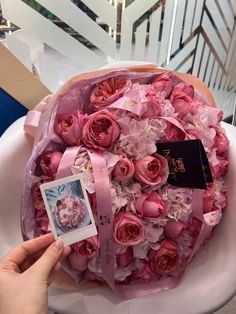 a bouquet of pink roses and flowers with a passport in the middle is being held by a woman