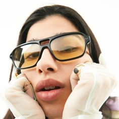 a woman in white gloves and glasses holding her hands to her face