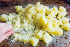 a person scooping potatoes into a baking pan