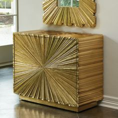 a golden cabinet with a mirror on top of it next to a window in a room