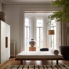 a living room filled with furniture and a large vase on top of a table next to a window