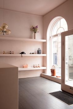 an empty room with shelves and vases on the wall next to a large window