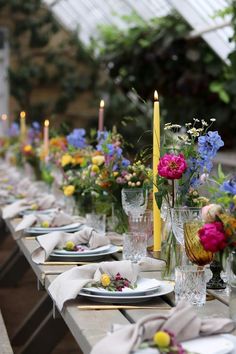 a long table is set with flowers and candles for an outdoor dinner or party event