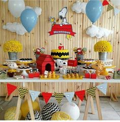 a table topped with lots of cakes and desserts covered in yellow and blue balloons