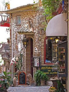 an old brick building with lots of potted plants on the outside and in front