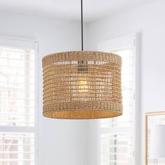 a rattan light fixture hanging from a ceiling in a room with white walls and windows