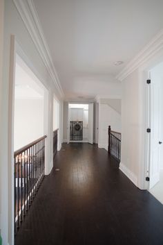 an empty hallway with hard wood floors and white walls