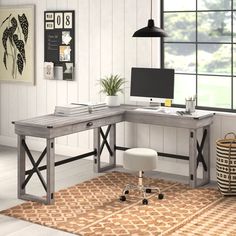 a computer desk sitting on top of a rug next to a window