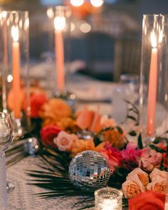 the table is set with candles, flowers and disco ball centerpieces on it