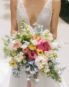 a bridal holding a bouquet of flowers in her hand and wearing a beaded dress