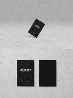 two black and white business cards sitting on top of a cement wall next to each other