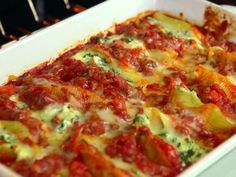 a casserole dish with tomatoes, cheese and spinach