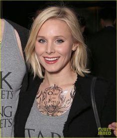 a woman with tattoos on her chest smiling at the camera