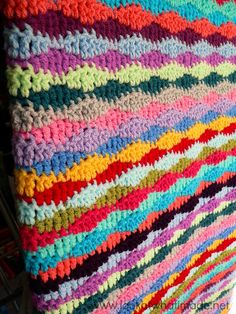 a multicolored crocheted blanket hanging on a wall