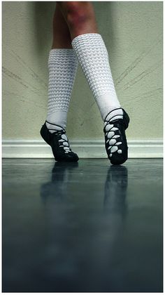 the legs and ankles of a woman in white socks with laces on them, standing against a wall