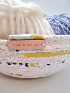 two balls of yarn are in a basket with a name tag that says mo bebell