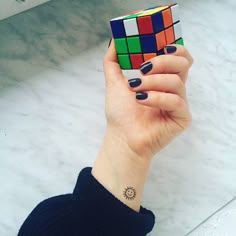 a woman's hand holding a rubik cube in front of her face,