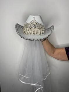 a bride's hat with the word bride on it being held up by her hands