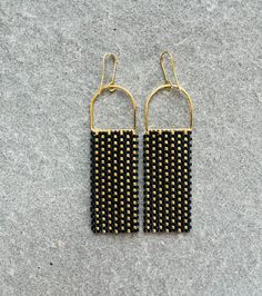 Black and Gold glass bead statement earrings inspired by a baltic basket weave motif. The beads sparkle beautifully in the light accentuating the basket weave pattern. Each bead is hand sown row after row. Glass beads reveal a beautiful shine as they catch the light. Could be worn daily or on a special occasion. Lightweight and sturdy design! Make a statement with these handmade bead earrings with a modern and bold design.  Minimalist with a pop of color to brighten up any outfit or occasion. 14K plated gold earring components. The earrings are handmade by me in my tiny studio in Minneapolis. Elegant Woven Drop Earrings, Black Handwoven Drop Earrings, Handwoven Black Drop Earrings, Elegant Woven Dangle Earrings, Elegant Gold Woven Earrings, Black Earrings With Handwoven Round Beads, Handmade Elegant Rectangular Beaded Earrings, Elegant Woven Dangle Jewelry, Black Handwoven Earrings With Round Beads