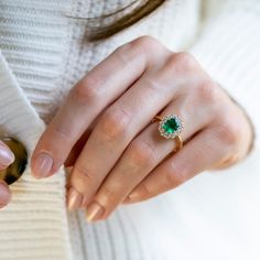 a close up of a person wearing a ring with a green stone in the middle