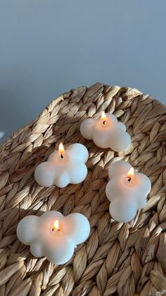 three white candles sitting on top of a woven basket