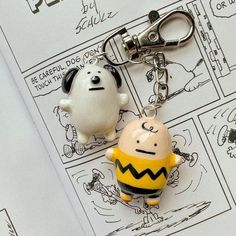 two cartoon key chains sitting on top of a piece of paper next to each other