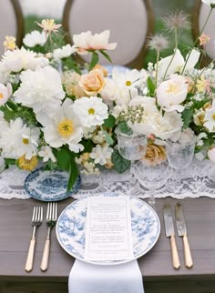 the table is set with plates, silverware and floral centerpieces on it