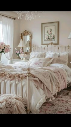 a white bed sitting in a bedroom next to a chandelier and window with curtains