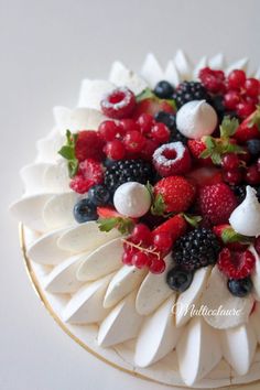 a white cake topped with berries, raspberries and other toppings on top of it