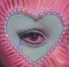 an eye with long lashes and pearls on it is seen through the center of a pink heart