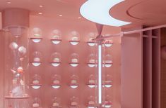 a room with pink walls and lots of cupcakes on display in glass domes