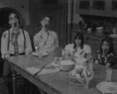 an old black and white photo of people sitting at a table with food in front of them