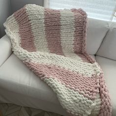 a pink and white blanket sitting on top of a couch