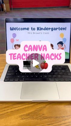 an open laptop computer sitting on top of a wooden table with a sign reading welcome to kindergarttown