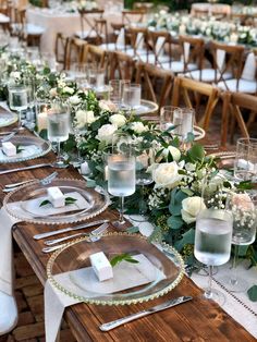 the table is set with white flowers and greenery for an elegant dinner or reception