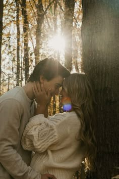 a man and woman standing next to each other in front of trees with the sun shining on them