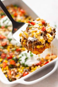 a spoon full of mexican casserole with corn on the cob