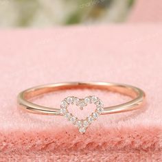 a heart shaped diamond ring sitting on top of a pink blanket