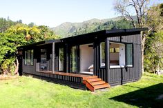 a small black house sitting on top of a lush green field