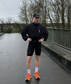 a man standing in the middle of a road wearing shorts and an orange tennis shoe