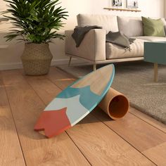 a surfboard laying on the floor in front of a couch and potted plant