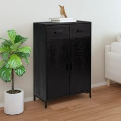 a black cabinet next to a white couch and a potted plant in a living room