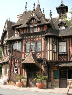 an old building with many windows and plants in pots on the side of the street