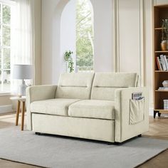 a white couch sitting on top of a rug in a living room next to a window