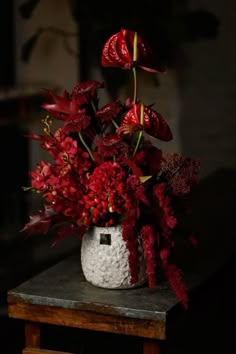 a white vase filled with red flowers on top of a table