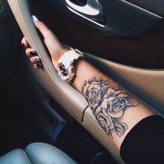 a woman's arm with a rose tattoo on it sitting in the driver's seat